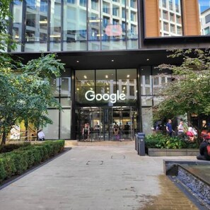 A Google store entrance with a glass facade, a paved walkway, and greenery. - London Apartment - Near King’s Cross St Pancreas! (Greater London)
