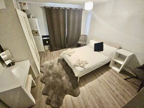 Una habitación de hotel con cama, mesitas de noche, una silla, escritorio y armario.