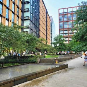 A modern urban plaza with a water feature, surrounded by buildings with large windows and a mix of glass and brick facades. - London Apartment - Near King’s Cross St Pancreas! (Greater London)