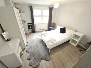 A modern bedroom with a bed, bedside tables, a wardrobe, a radiator, and a window with curtains. - London Apartment - Near King’s Cross St Pancreas! (Greater London)