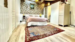 A bedroom with a large bed, a patterned rug, a skylight, and a wardrobe. - Gorgeous 5 Bedroom Parisian Home (Paris)