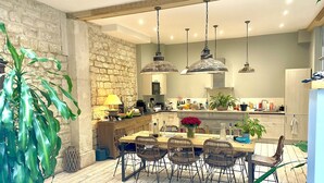 A modern kitchen with a stone wall, wooden flooring, and a dining area with wicker chairs. - Gorgeous 5 Bedroom Parisian Home (Paris)