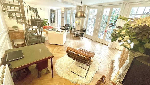A spacious living room with a wooden floor, a dining area with a table and chairs, a staircase, and large windows allowing natural light. - Gorgeous 5 Bedroom Parisian Home (Paris)