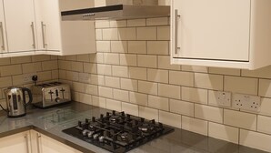 Une cuisine moderne avec des meubles blancs, une cuisinière à gaz, un grille-pain et une bouilloire.