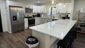 A modern kitchen with white cabinets, stainless steel appliances, and a large island. - Lake front 2.5 miles from Clemson  with private cove  (Central)