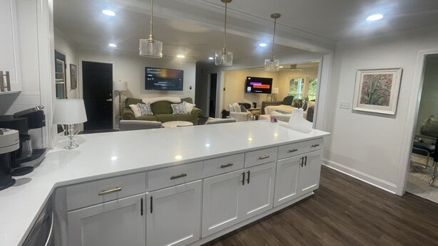 A modern kitchen with a large island, white cabinetry, and pendant lighting. - Lake front 2.5 miles from Clemson  with private cove  (Central)