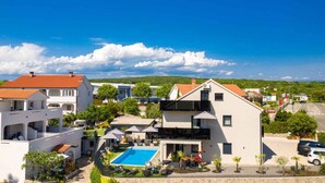 A residential area with a swimming pool, white buildings, and a clear blue sky. - Holiday apartment modernly furnished with swimming pool (Krk)