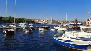 A marina with various boats docked, a clear blue sky, and a town in the background. - Holiday apartment modernly furnished with swimming pool (Krk)