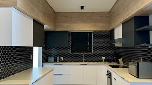 A modern kitchen with white cabinetry, black and white hexagonal backsplash, and a central island. - Captivating Home with Mountain Views/Proximity to the Beach Your Perfect Getaway (Cape Town)