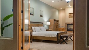 Une chambre à coucher comprenant un lit, des tables de chevet, un banc, une armoire et une cheminée.