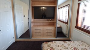 Ein Schlafzimmer mit einem Spiegelkleiderschrank, einem Bett und einem Fenster mit Jalousien.