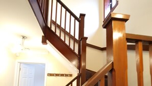 Eine Holztreppe mit Handlauf und Teppichstufen, die zu einer oberen Etage führt.