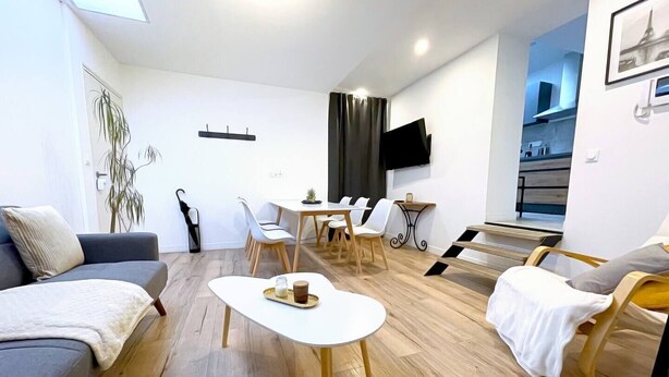 Una sala de estar moderna y bien iluminada, con un sofá, una mesa de centro y un comedor con sillas y una mesa.