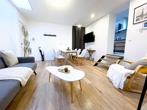 Un salon moderne et bien éclairé, comprenant un canapé, une table basse et un coin repas avec des chaises et une table.