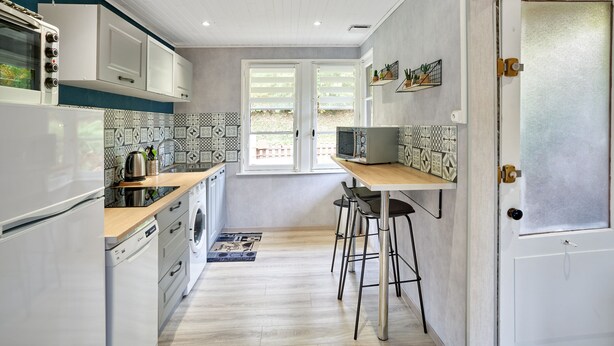 A compact kitchen with white appliances, a wooden countertop, and a window with blinds. - Chalet de la Soye (Pierre-Percée)