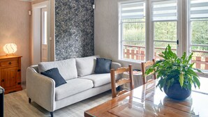 A modern living room with a sofa, a dining table, and a potted plant. - Chalet de la Soye (Pierre-Percée)