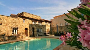 A stone building with a swimming pool, arched windows, and a tiled roof. - Groot Modern Appartement Mazet 21 Privé Terras, Dakterras en Gezamenlijk Zwembad (Le Plan-de-la-Tour)