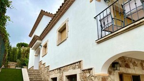 A two-story house with a stone facade, a balcony, and a wooden door. - Villa Cabañas with infinity pool, gardens and barbecue in Calonge, Costa Brava (Calonge)