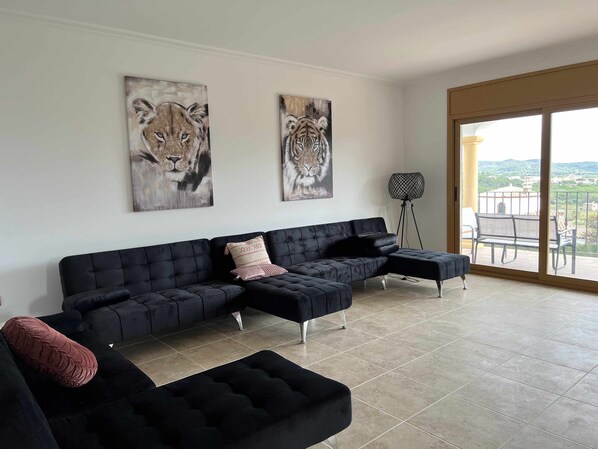 A modern living room with a sectional sofa, a floor lamp, and two large animal paintings on the wall. - Villa Cabañas with infinity pool, gardens and barbecue in Calonge, Costa Brava (Calonge)