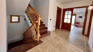 A staircase with wooden balusters leading to a landing, a tiled floor, and a door leading to another room. - Villa Cabañas with infinity pool, gardens and barbecue in Calonge, Costa Brava (Calonge)