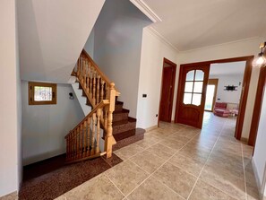 A staircase with wooden balusters leading to a landing, a tiled floor, and a door leading to another room. - Villa Cabañas with infinity pool, gardens and barbecue in Calonge, Costa Brava (Calonge)