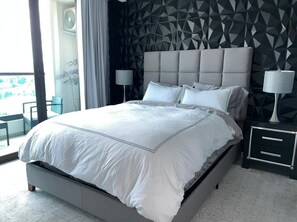 Ein modernes Schlafzimmer mit einem großen Bett, einer Wand mit geometrischem Muster und Blick auf einen Balkon.