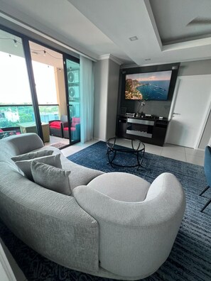 A modern living room with a sofa, a coffee table, and a flat-screen TV mounted on the wall.