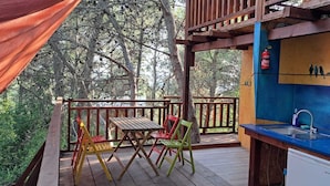 A wooden deck with a table and chairs, a sink, and a fire extinguisher. - TreeHouses Ljubač Glamping Robinson (Razanac)