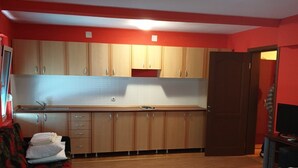 Een compacte kamer met kitchenette, bed, bank en televisie.