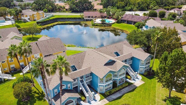 A residential area with a large pond, houses with blue and yellow exteriors, and a central swimming pool.