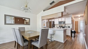 A modern kitchen with white cabinets, a central island, and stainless steel appliances.
