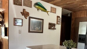 Une cuisine avec des meubles de rangement en bois, un plan de travail blanc et une décoration en forme de poisson suspendue.