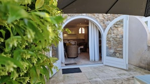 A covered outdoor area with a stone wall, a wicker chair, and a dining table. - Groot Appartement Prat L'estagnol 19 met Terras, Balkon en Gezamenlijk Zwembad (Le Plan-de-la-Tour)