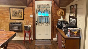 Ein gemütliches Zimmer mit Holzwänden, einer Tür mit gemusterten Vorhängen, einem Vintage-Radio und einer Puzzlebox auf der Anrichte.