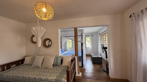 A bedroom with a bed, a hanging light fixture, a mirror, and a window with curtains. - Okomos Private Villa, Diani Beach Kenya (Diani Beach)