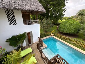 A pool area with a thatched-roof structure, a wooden deck, and a well-maintained garden. - Okomos Private Villa, Diani Beach Kenya (Diani Beach)