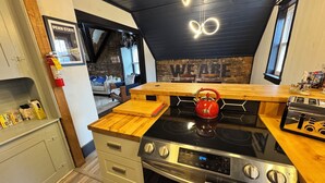 A compact kitchen with a gas stove, wooden countertop, and a red kettle. - Stylish, Historic PSU-themed Apt.—2 blocks from Waterfront (Bellefonte)