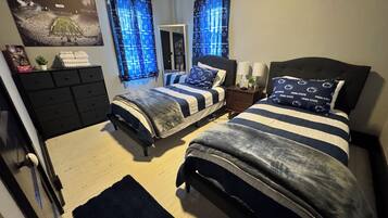A bedroom with two beds, a dresser, a mirror, and a window with curtains.