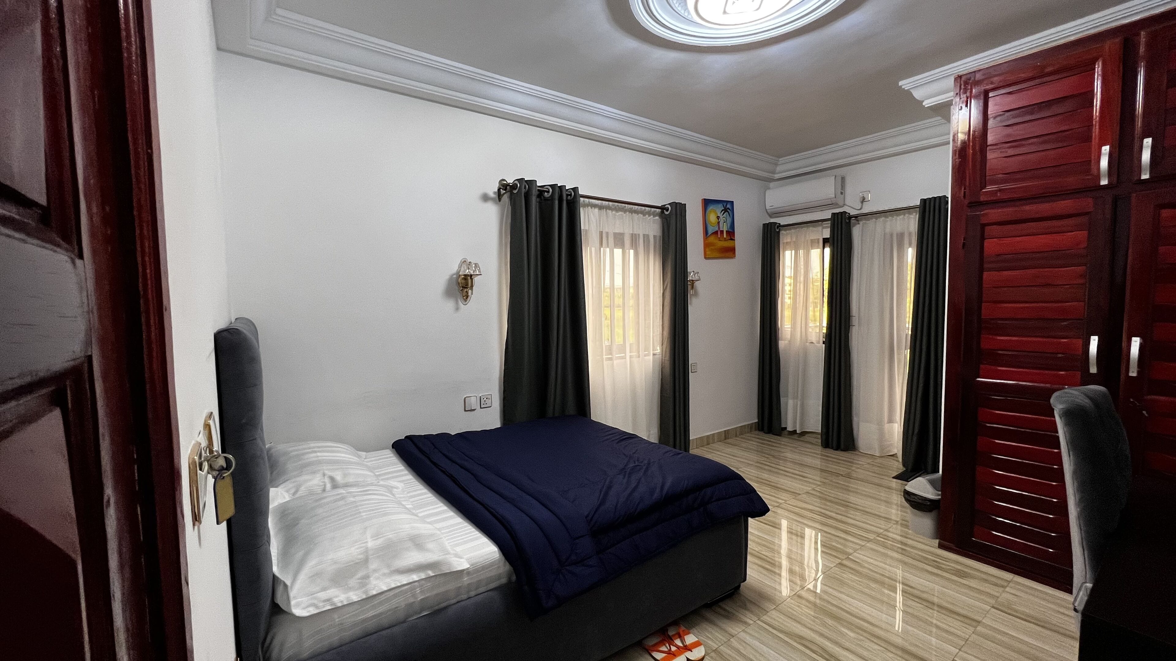 A bedroom with a bed, a wardrobe, a door, and a ceiling light.