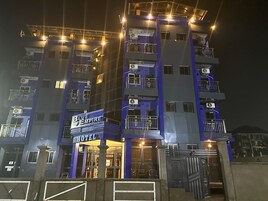 Um hotel com vários andares, varandas, aparelhos de ar condicionado e uma placa com a inscrição 'Blue Empire Hotel'.