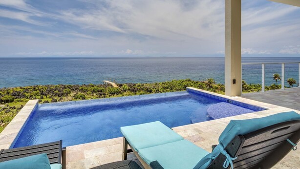 A pool area with lounge chairs and a view of the ocean. - Stunning Oceanfront 5 Bed House with Infinity Pool (West Bay)