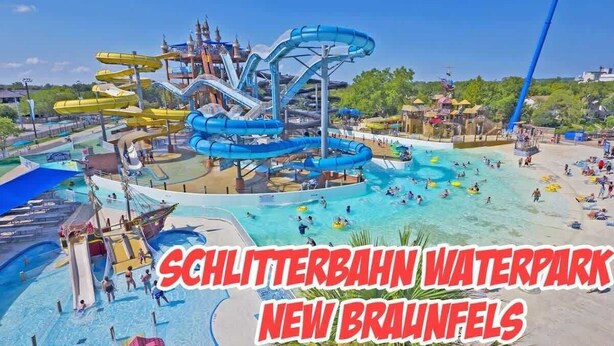 Un parque acuático con múltiples toboganes y piscinas, incluyendo un gran tobogán azul y uno más pequeño de color blanco.