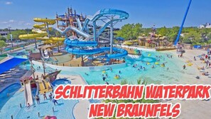 A water park with multiple slides and pools, including a large blue water slide and a smaller white slide.