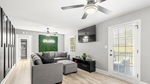 Ein modernes Wohnzimmer mit einem grauen Ecksofa, einer schwarzen Unterhaltungsecke und einem Deckenventilator.