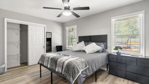Ein Schlafzimmer mit einem Bett, einem Schminktisch, einem Deckenventilator und einem Fenster mit Jalousien.