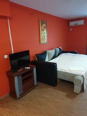 A bedroom with a bed, a TV on a wooden stand, and an air conditioning unit on the wall. - Vila Elkom Apartment 16 (Ulcinj)