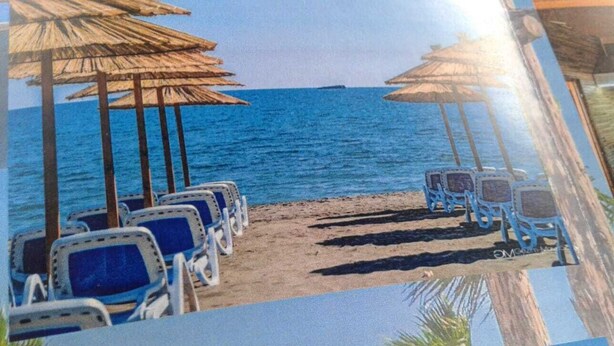 Una spiaggia con file di sedie a sdraio blu e ombrelloni di paglia.