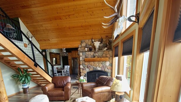 A spacious living room with leather sofas, a patterned rug, and a stone fireplace. - Three bedroom,  two bath on the Middle Fork of Rock Creek (Philipsburg)