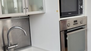 Una cucina moderna con mobili bianchi, un lavello in acciaio inossidabile, un forno a microonde e un forno.