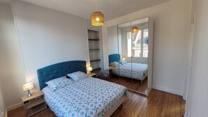 Una camera da letto con un letto grande, un armadio, uno specchio e una lampada a sospensione.